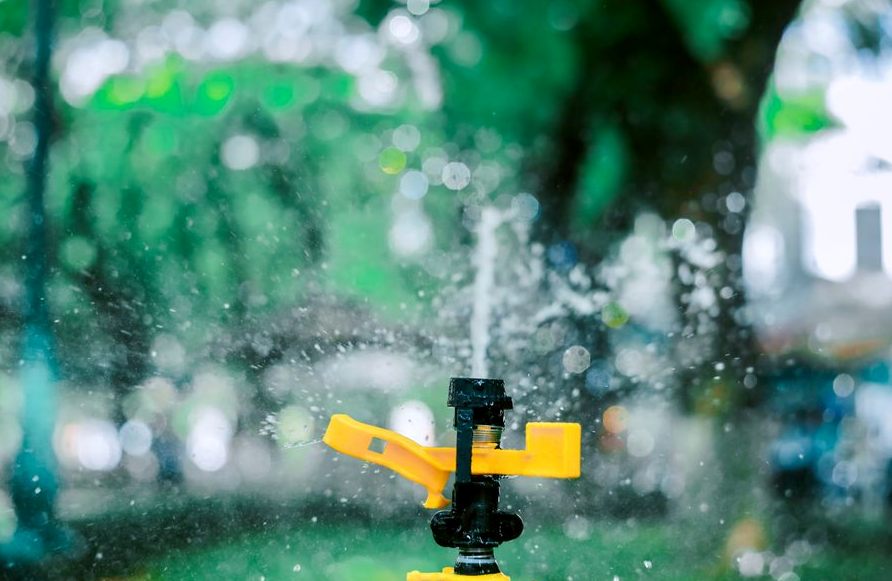 Close-up of a yellow garden sprinkler with blurred background creating a bokeh effect